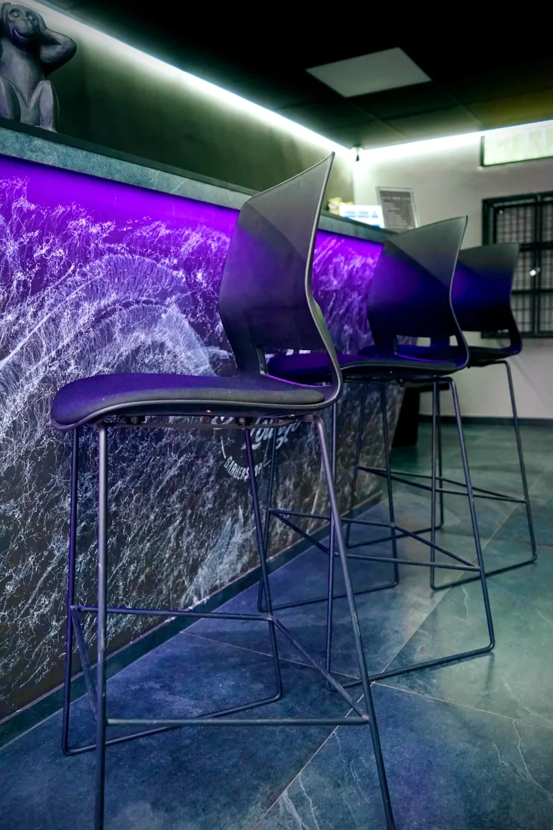 Bar stools along the purple-lit counter